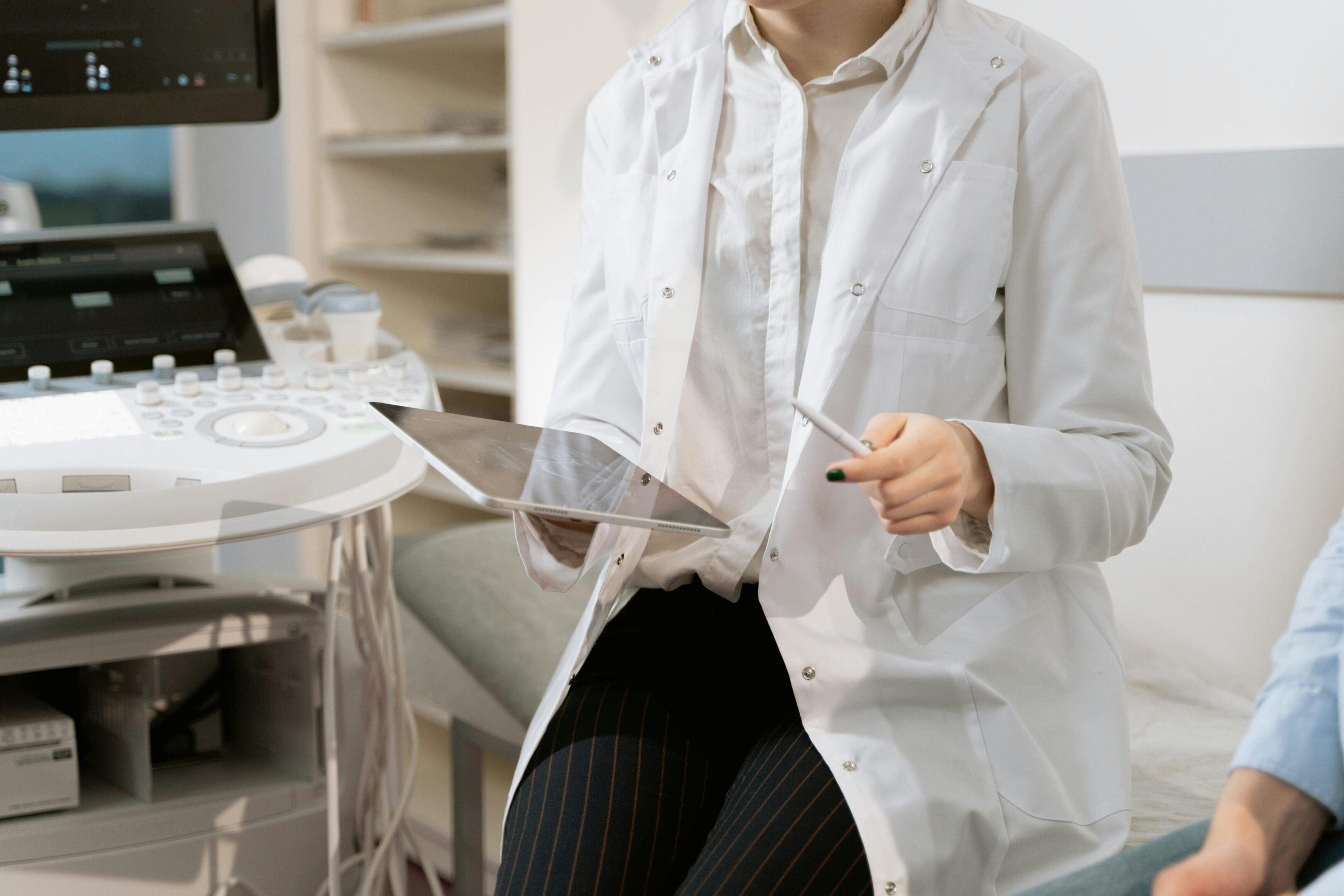 A woman in white coat holding a tablet.